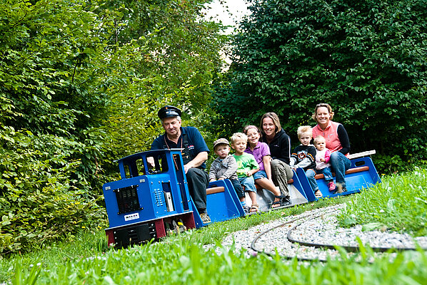 Kinder fahren mit einem kleinen Zug der Bockerlbahn beim Bergbaumuseum in Peißenberg.